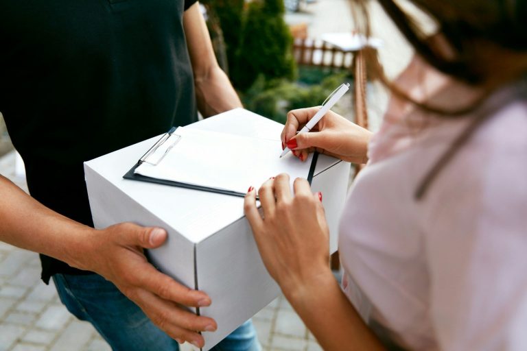A person receiving a package and signing for it with a pen.